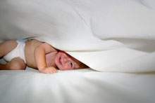 infant on white cotton bedsheets